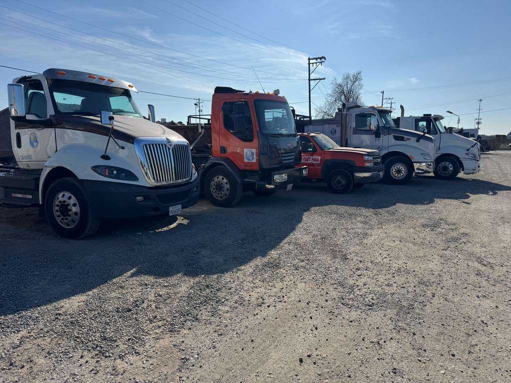 Specialized Fleet and Support Vehicles Wide-angle shot of a multi-vehicle commercial hauling fleet parked together at an operational facility yard.